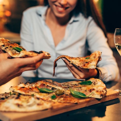 close up of people eating pizza.